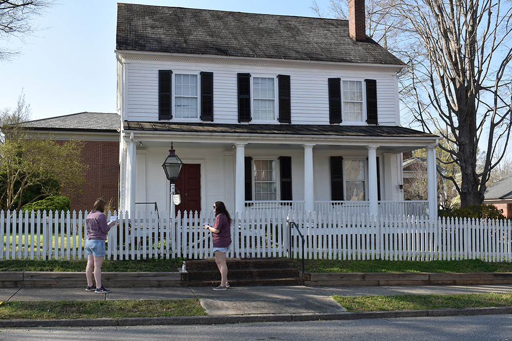 Emily Rider and Emalee Young stand outside the Utzman-Chambers House on S. Jackson Street to discuss the answer.